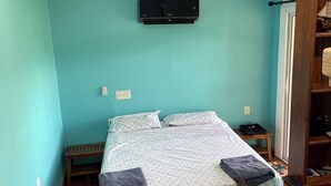 Een slaapkamer met een bed, een plafondventilator, een tv aan de muur en een houten kledingkast.