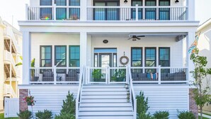 A two-story house with a front porch, a staircase, and a flag. - Rooftop Sunsets • Ocean Glimpse • Sleeps 10 (Ocean City)