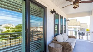 A balcony with a wicker sofa, a ceiling fan, and a view of the neighborhood. - Rooftop Sunsets • Ocean Glimpse • Sleeps 10 (Ocean City)