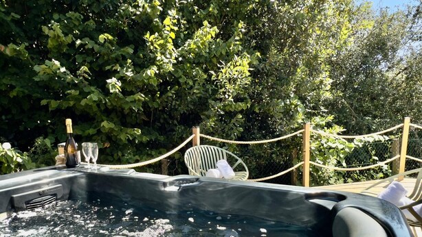 Un jacuzzi con burbujas, rodeado de follaje y una barrera de cuerda.