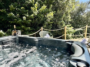 A hot tub with bubbles, surrounded by greenery and a rope barrier.