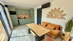 Un espacio habitable moderno con un sofá, una mesita de centro y una cocina al fondo.