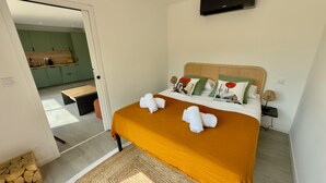 Un dormitorio con cama, mesita de noche, lámpara y vistas a una cocina.