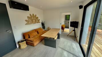 Una sala de estar moderna con un sofá, una mesa de madera y un televisor sobre un mueble.
