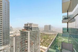Um edifício alto com várias varandas, vista clara da paisagem urbana e um parque na área inferior.
