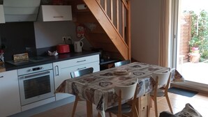 Een keuken met een eettafel en stoelen, een trap en uitzicht op het buitenland.