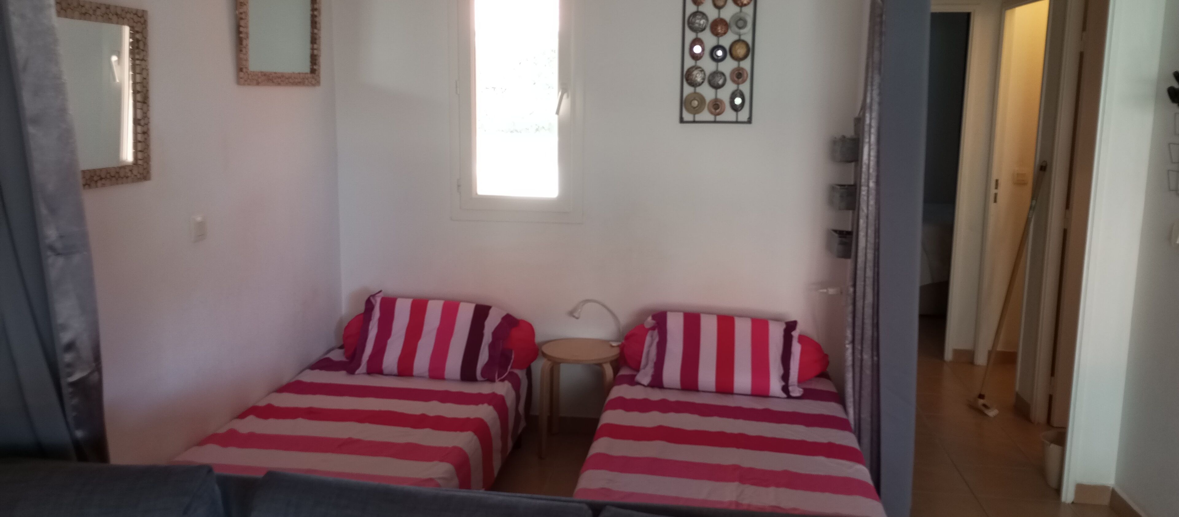 Una habitació amb dos llits, una taula petita i una finestra.