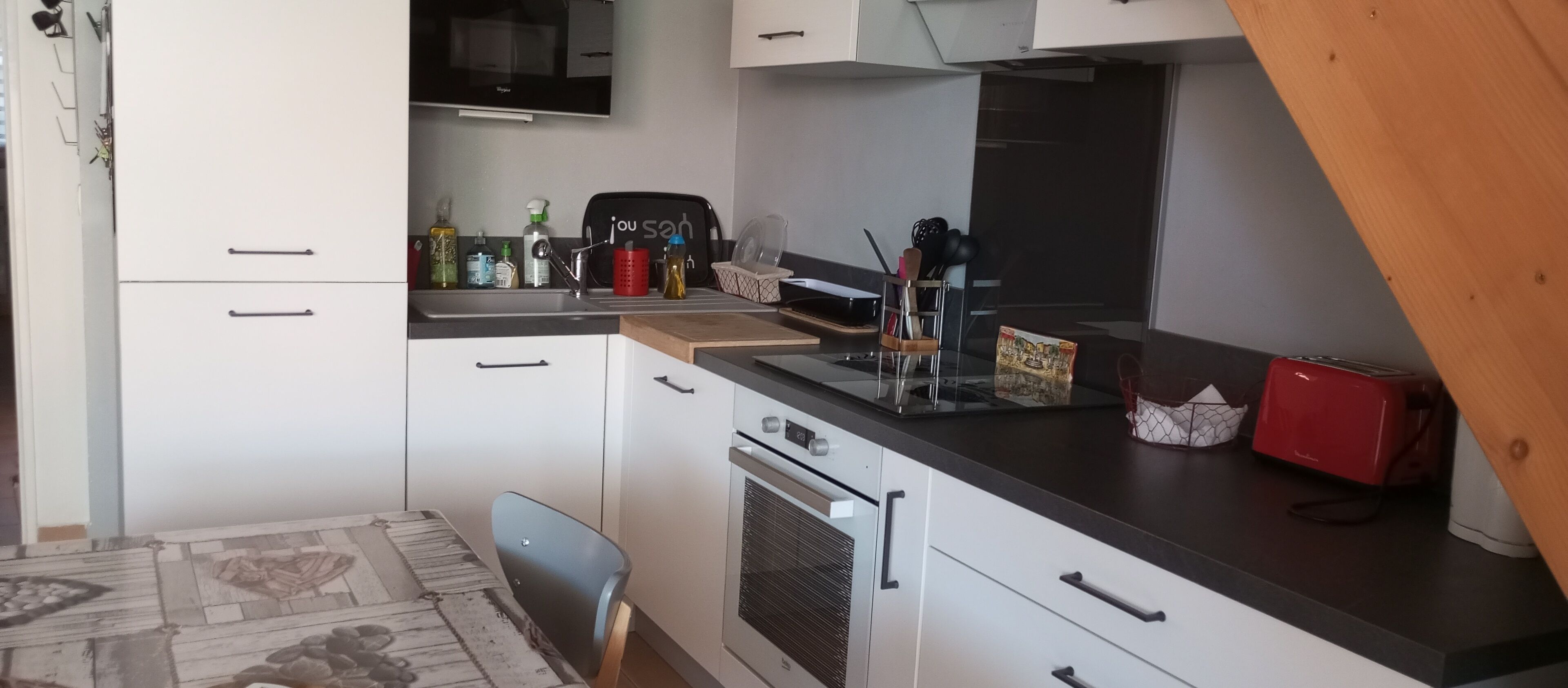 A modern kitchen with white cabinets, a black countertop, a built-in oven, and a microwave.