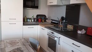 Een moderne keuken met witte kasten, een zwart aanrecht, een inbouwoven en een magnetron.