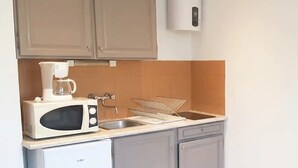 A compact kitchen with a microwave, coffee maker, sink, and a small refrigerator.