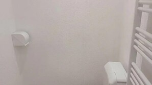 A small, white bathroom with a toilet, a hand dryer, and a radiator.