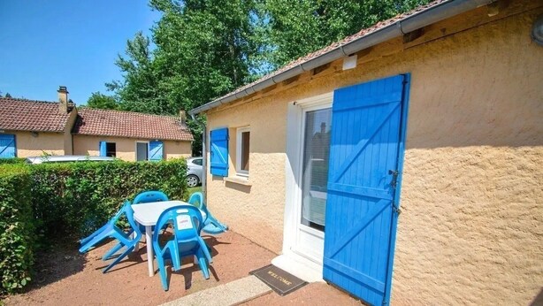 A small building with a blue door, a window, and a table with blue chairs outside.