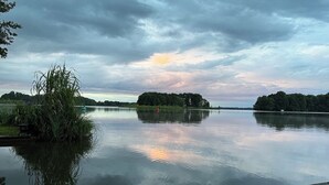 A calm lake with a wooden dock, surrounded by trees and vegetation. - Houseboat Queen Emma! Deep relaxation on gently rocking waves!!! (Zehdenick)
