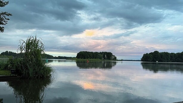 A calm lake with a wooden dock, surrounded by trees and vegetation. - Houseboat Queen Emma! Deep relaxation on gently rocking waves!!! (Zehdenick)