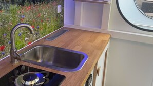 A compact kitchenette with a gas stove, stainless steel sink, and a window overlooking a garden. - Houseboat Queen Emma! Deep relaxation on gently rocking waves!!! (Zehdenick)