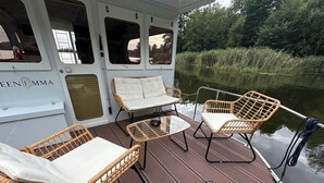 A boat deck with wicker furniture, a small table, and a grill. - Houseboat Queen Emma! Deep relaxation on gently rocking waves!!! (Zehdenick)