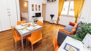 Un espacio habitable compacto con comedor, sofá y televisor.