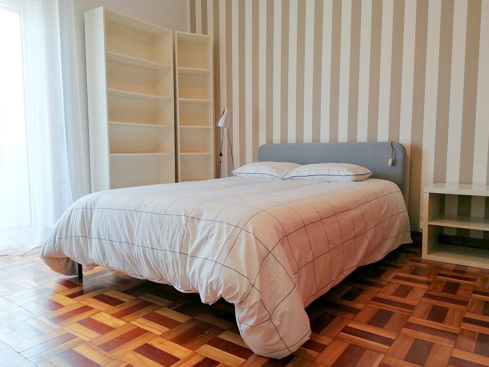 Een slaapkamer met een bed, een kledingkast en een nachtkastje.