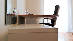Habitación de hotel con escritorio, silla y un espejo grande. Hay dos botellas sobre el escritorio.