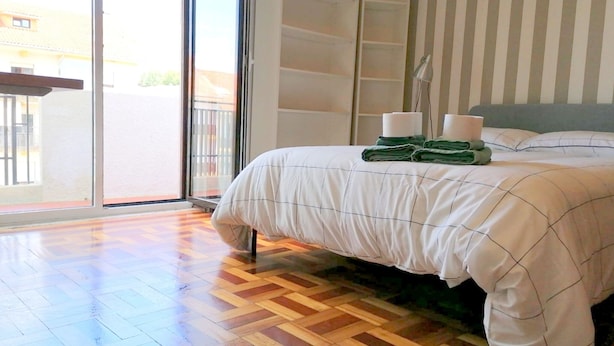 Un dormitorio con una cama grande, un ventanal corredero y vistas al exterior.