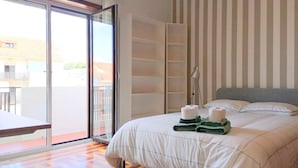 Una habitación de hotel con cama, balcón y pared a rayas.