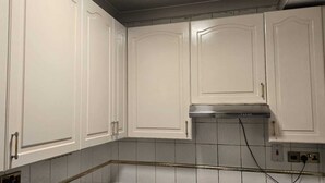 A kitchen with white cabinets, a stainless steel range hood, and tiled backsplash.