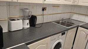 A kitchen with a toaster, a blender, a washing machine, and a sink.