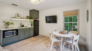 Eine moderne Küche mit integriertem Mikrowellenherd, Kühlschrank und Essbereich mit Tisch und Stühlen.