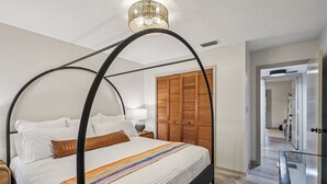 Ein modernes Schlafzimmer mit einem Himmelbett, einem Holzschrank und einer gläsernen Wendeltreppe.