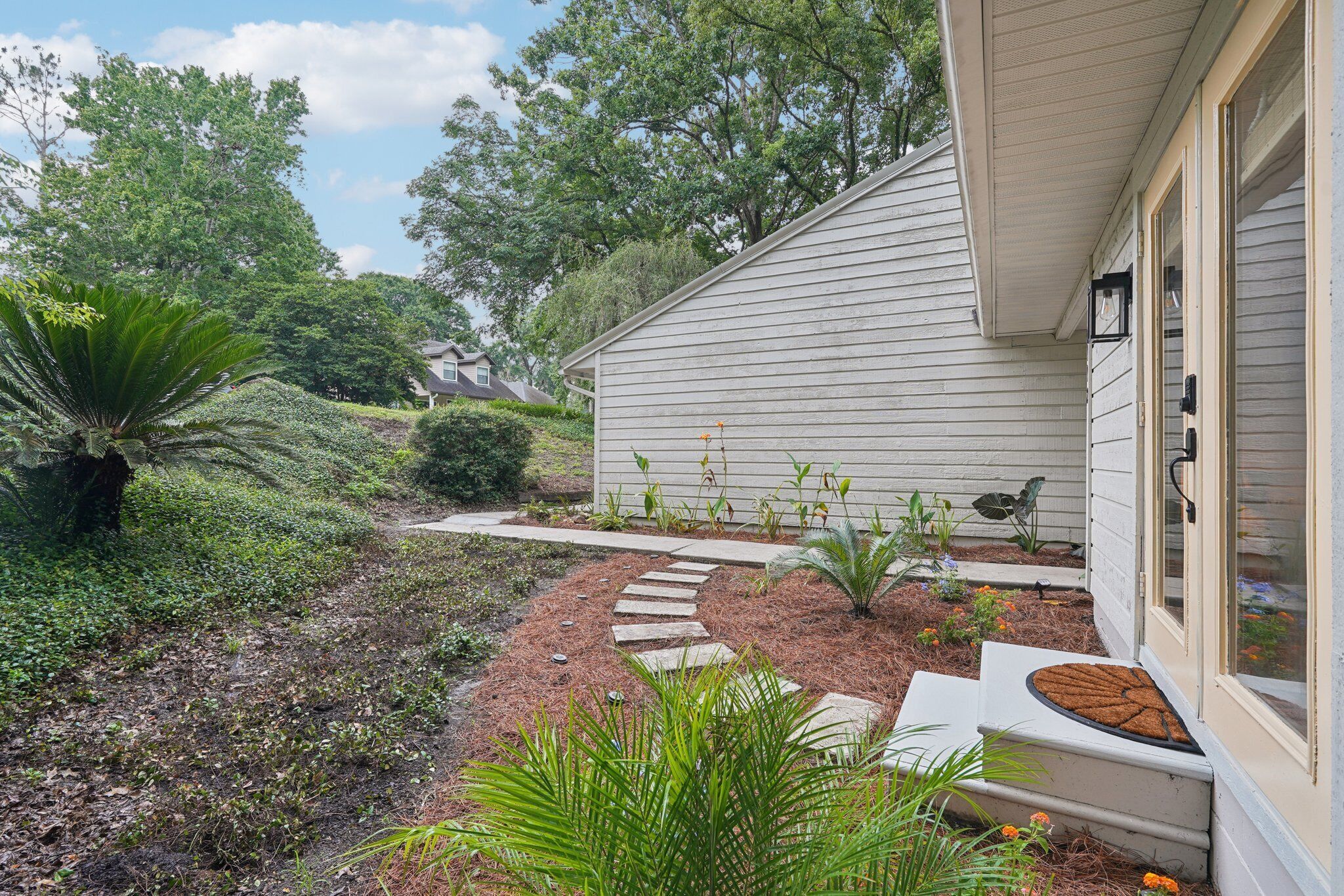 A house with a garden pathway leading to the front door, surrounded by various plants and shrubs.