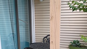 Eine Terrasse mit Tisch und Stühlen, eine Glasschiebetür, eine Wandleuchte und ein Blumentopf.