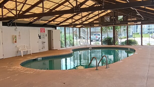 Ein überdachter Innenpool mit Poolleiter und einem weißen Stuhl in der Nähe.