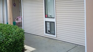 Ein Gebäude mit überdachter Veranda, einem Fenster mit Klimaanlage und einer Tür mit einem Kranz.