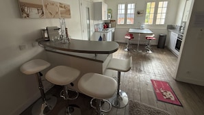 Een moderne keuken met een bar, witte kasten en een houten vloer.