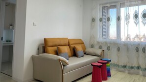 A living room with a sofa, a window with decorative curtains, and a small table with stools. - Marvelous 2-bedroom apartment with WiFi in Yantai (Yantai)