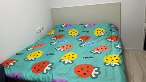 A bed with a teal bedspread featuring strawberry patterns and the word "Hello" repeated. - Marvelous 2-bedroom apartment with WiFi in Yantai (Yantai)