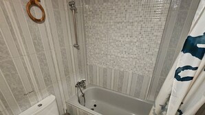 Une salle de bain avec une baignoire, des toilettes et une douche.
