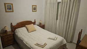 Un lit bien fait, avec une tête de lit en bois, deux tables de chevet avec des lampes et une fenêtre avec des rideaux.