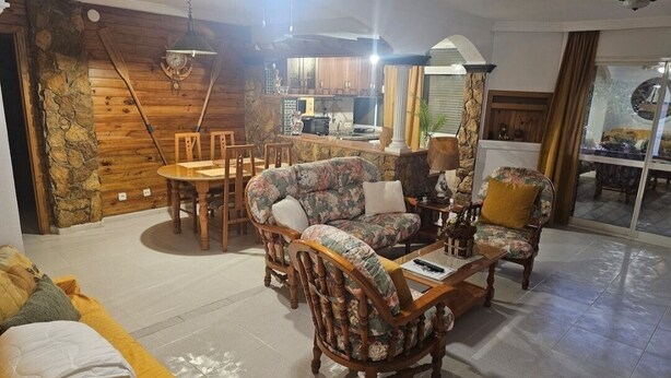 Un salon confortable avec un canapé, des fauteuils, une table basse et un coin repas.