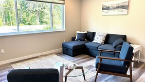 Ein modernes Wohnzimmer mit einem Ecksofa, einem kleinen Tisch und einem Sessel.