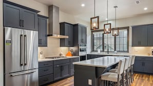 A modern kitchen with dark cabinets, stainless steel appliances, and a central island with bar stools.