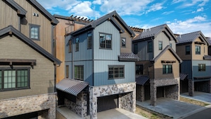 A row of modern townhouses with stone foundations, large windows, and attached garages.