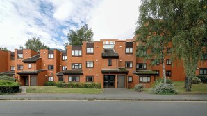 Ein mehrstöckiges Wohnhaus mit Backsteinfassade, zahlreichen Fenstern und einem zentralen Eingang.
