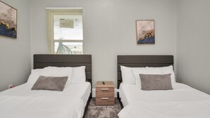 Une chambre d’hôtel avec deux lits, une petite table de chevet en bois et une fenêtre avec des stores.