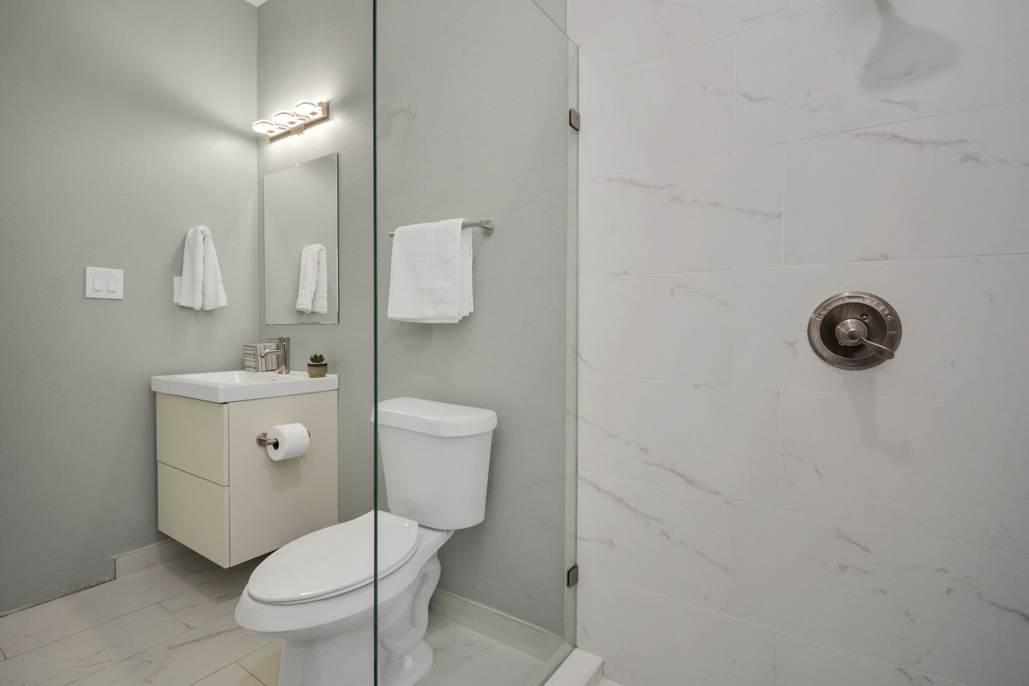 A modern bathroom with a toilet, sink, and shower area.