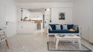 A modern living room with a white sofa, a coffee table, and a kitchen in the background.