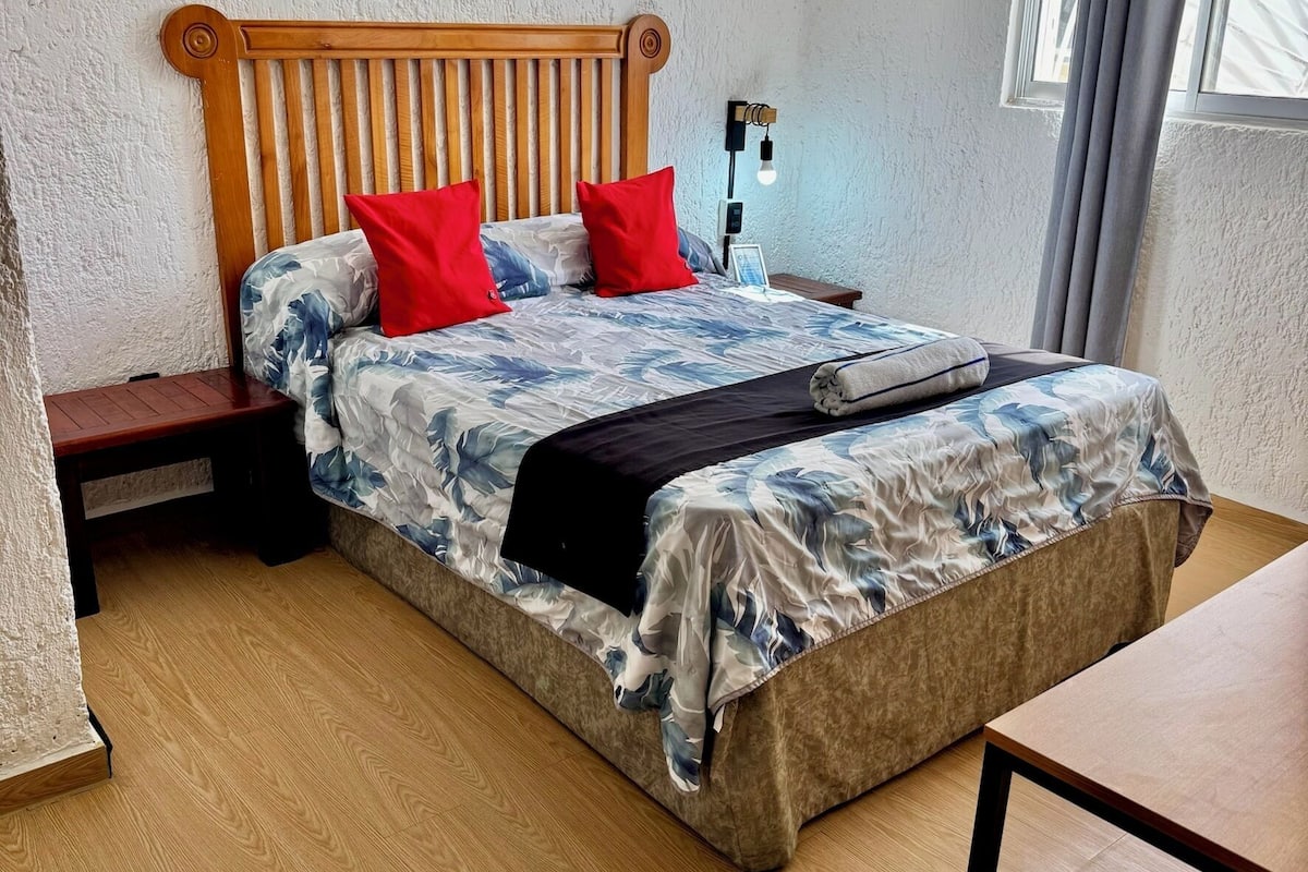 A bed with a wooden headboard, red pillows, and a floral bedspread.