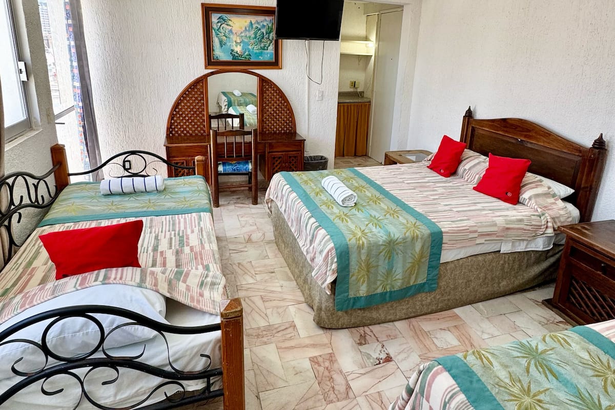 A hotel room with two beds, a desk, a chair, and a television.