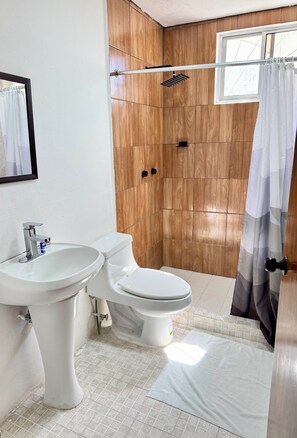 A bathroom with a wooden wall, a shower, a toilet, and a sink. - HOTEL FARALLON INN (Cancun)