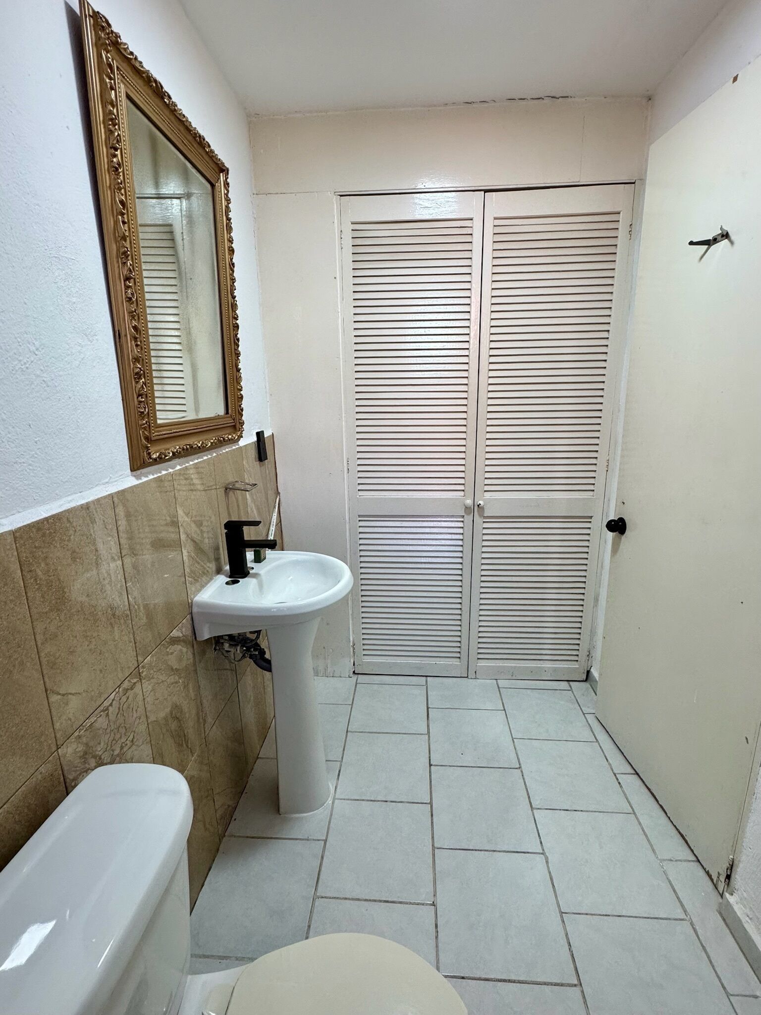 A bathroom with a toilet, sink, and mirror.
